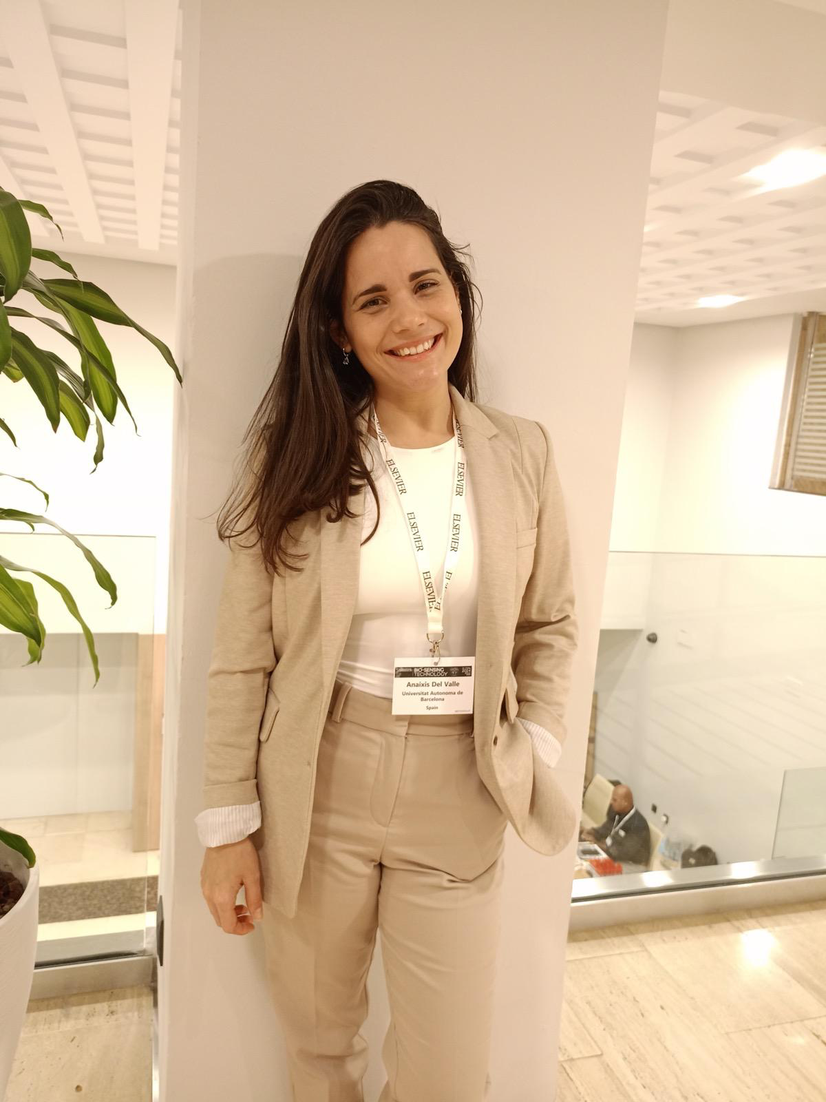 Anaixis sonriendo, con un traje beige, en un encuentro científico